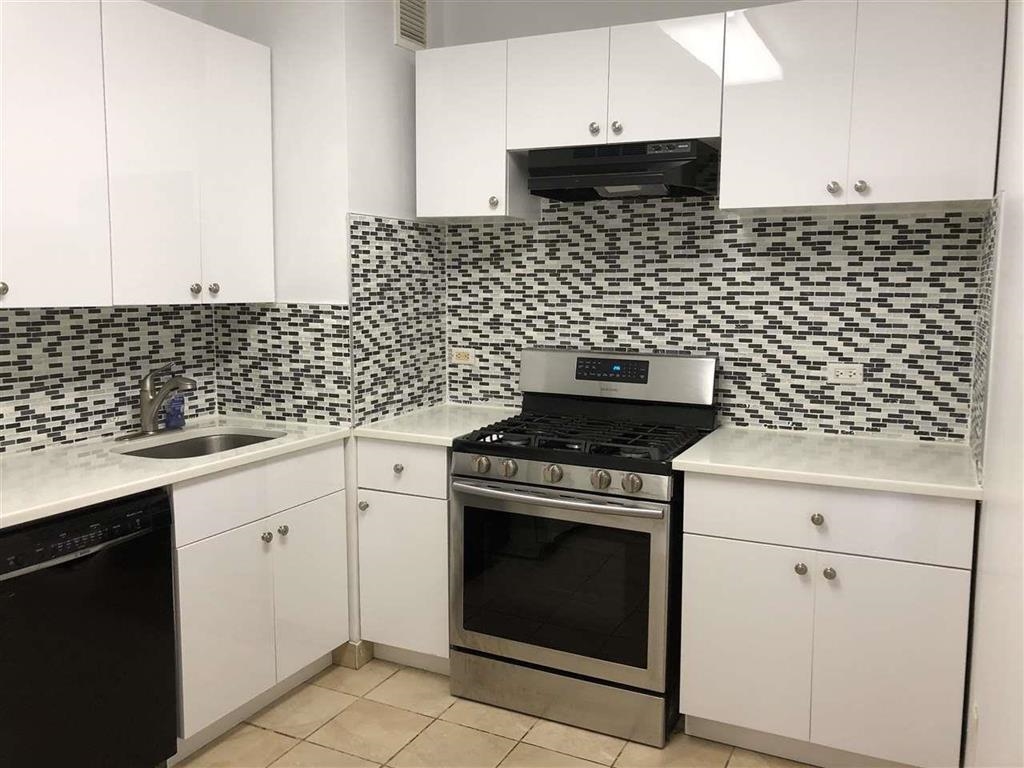 a kitchen with a stove and white cabinets