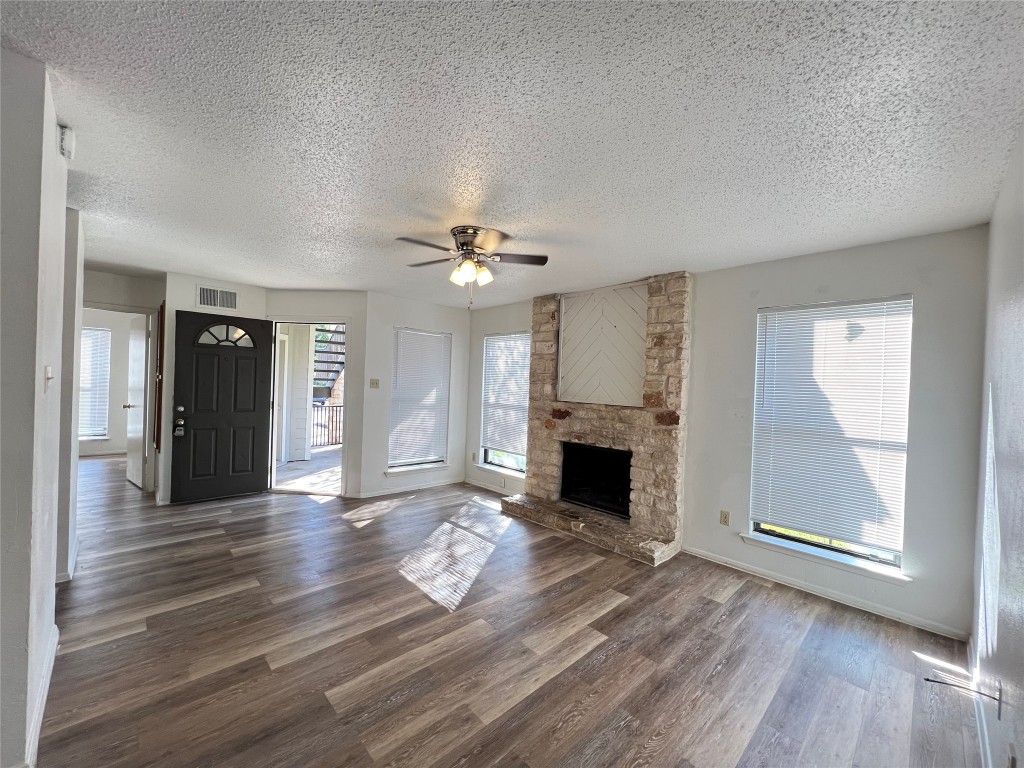 a view of an empty room with wooden floor fireplace and a window