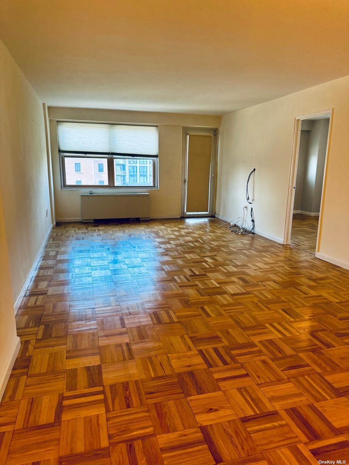 a view of an empty room with window and wooden floor