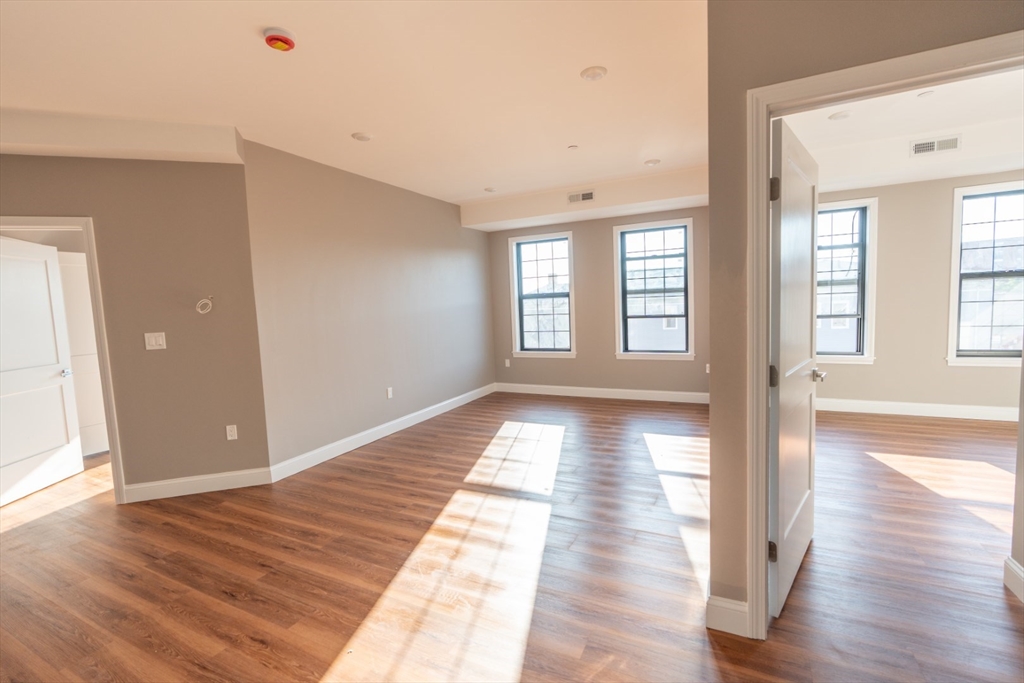 a view of empty room with wooden floor and fan