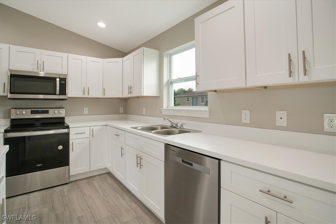 a kitchen with cabinets appliances a sink and a window