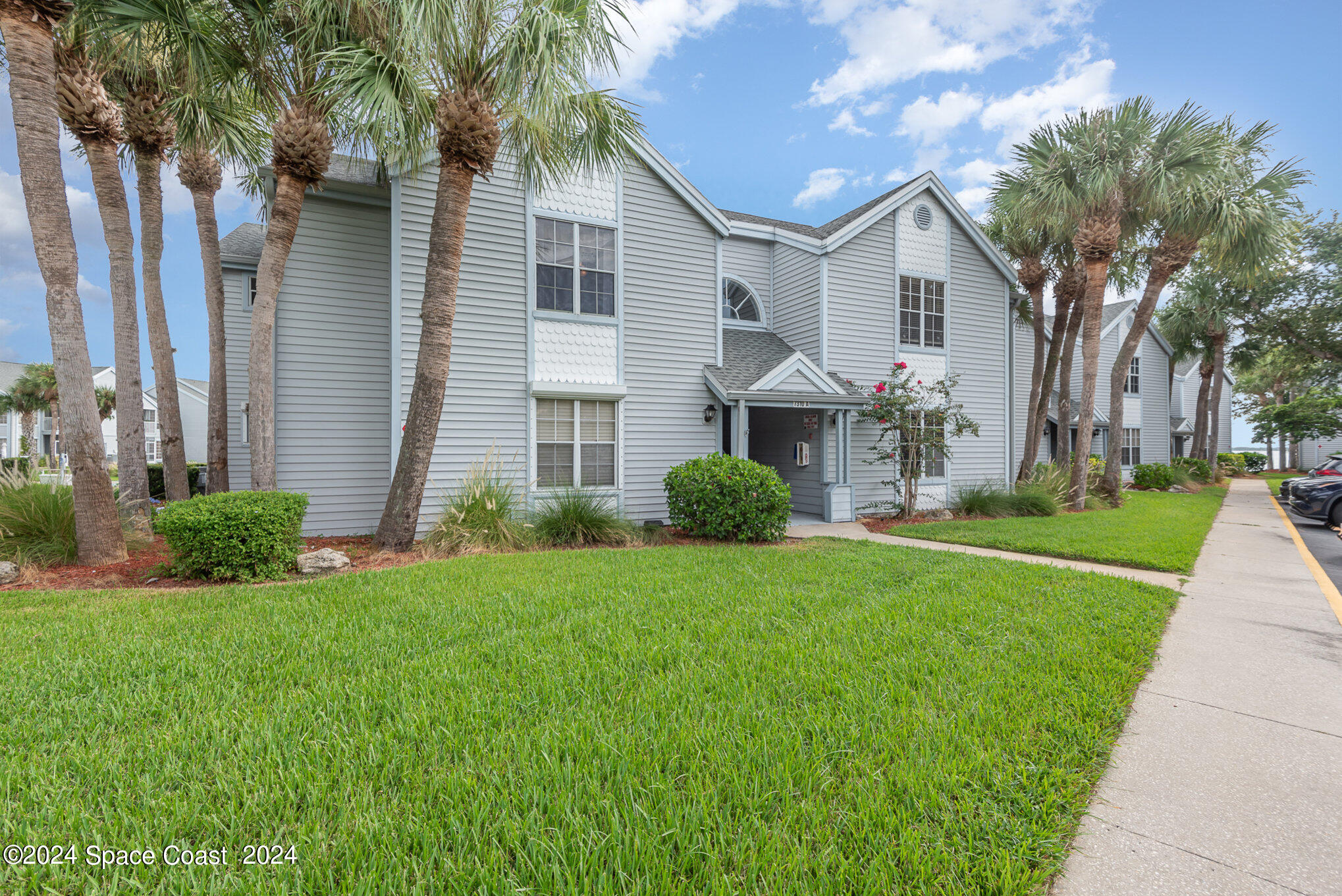 a front view of a house with a yard and palm trees