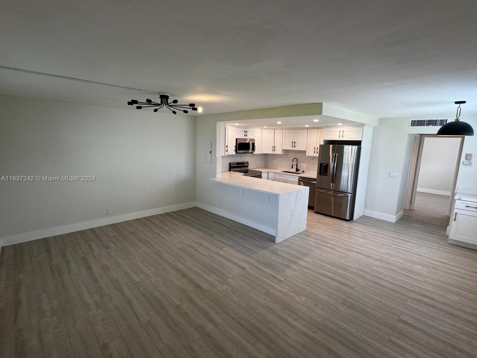 a view of a kitchen with a sink stove cabinets and empty room