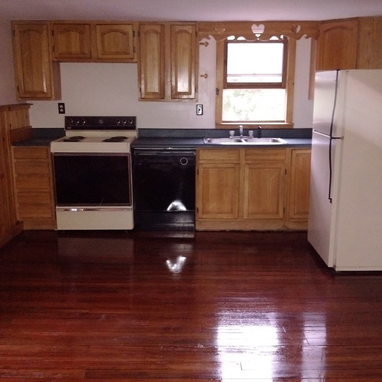 a kitchen with granite countertop a stove a sink and a refrigerator