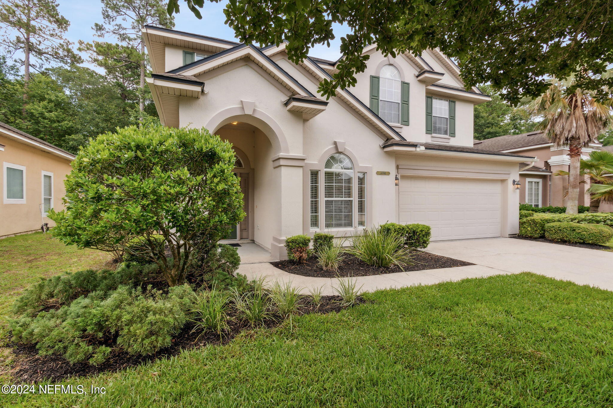 a front view of a house with a yard and potted plants