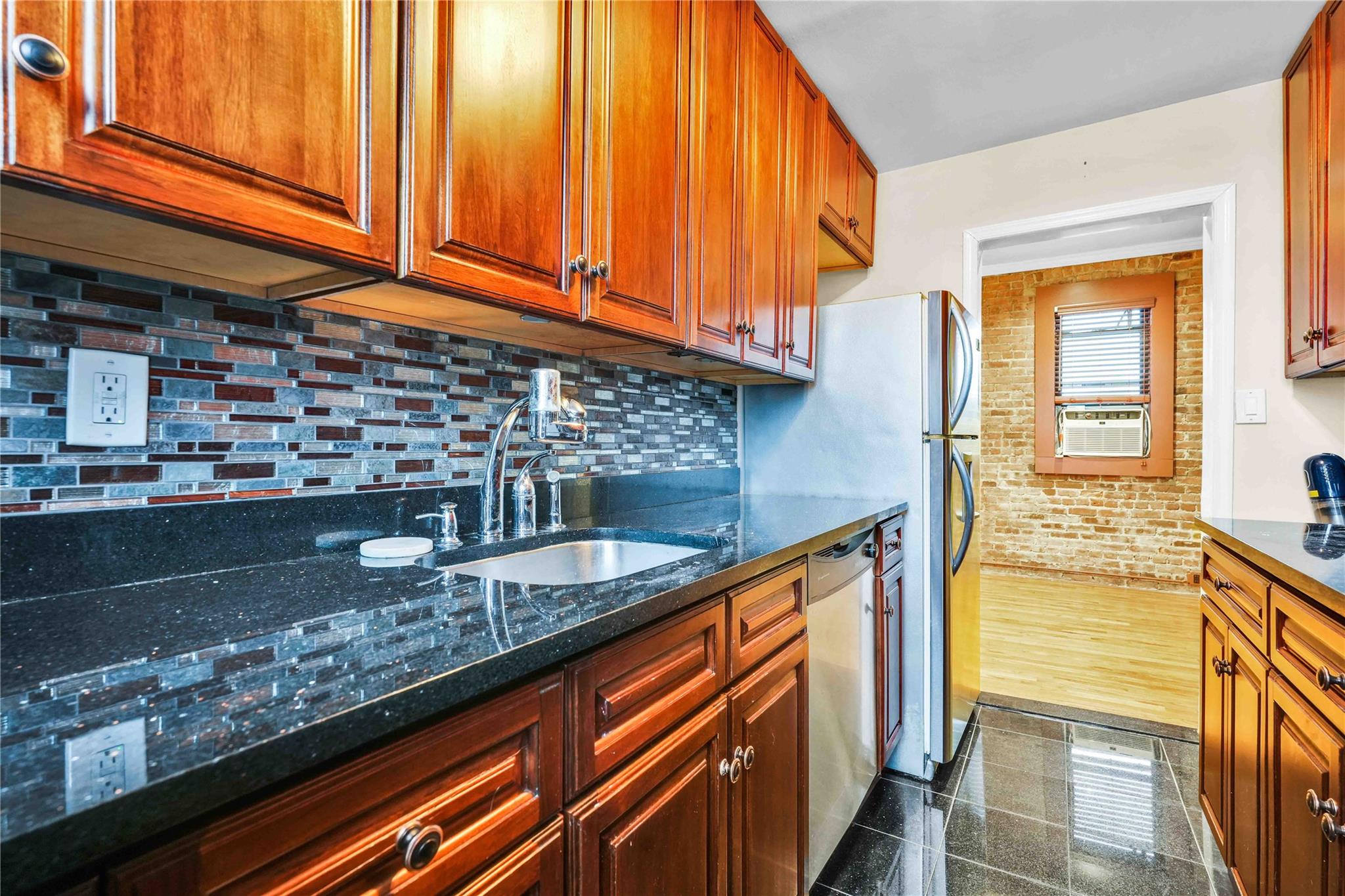 Kitchen featuring dark stone counters, cooling unit, sink, stainless steel dishwasher, and dark hardwood / wood-style flooring