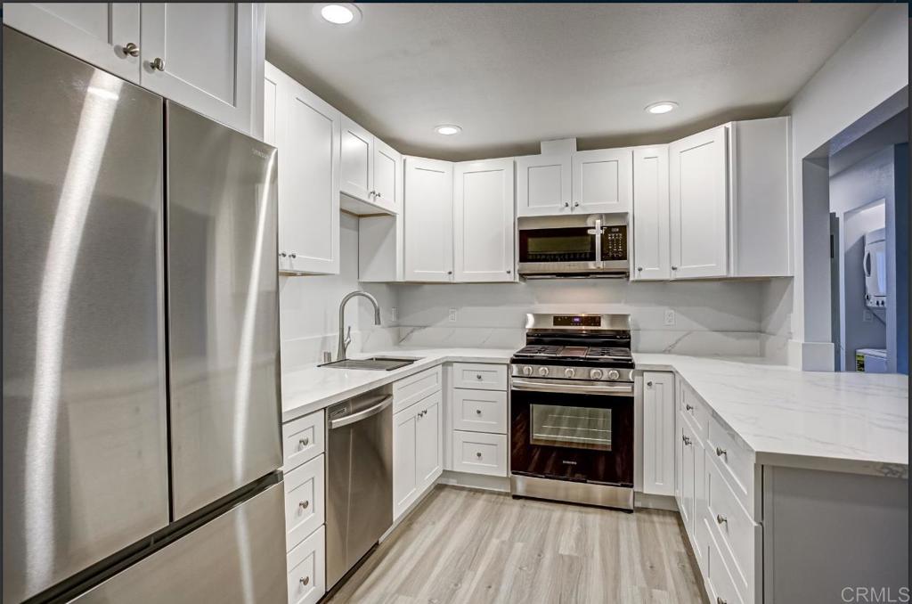 a kitchen with stainless steel appliances granite countertop a stove refrigerator sink and microwave