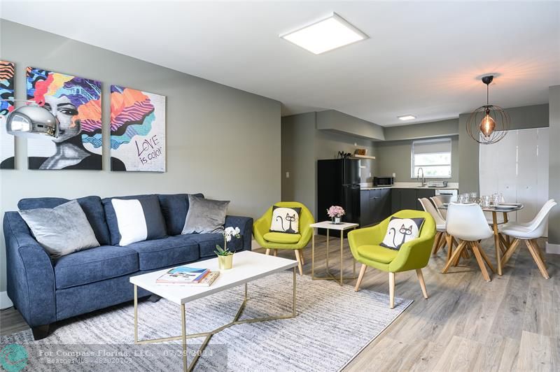 a living room with furniture and a dining table with wooden floor