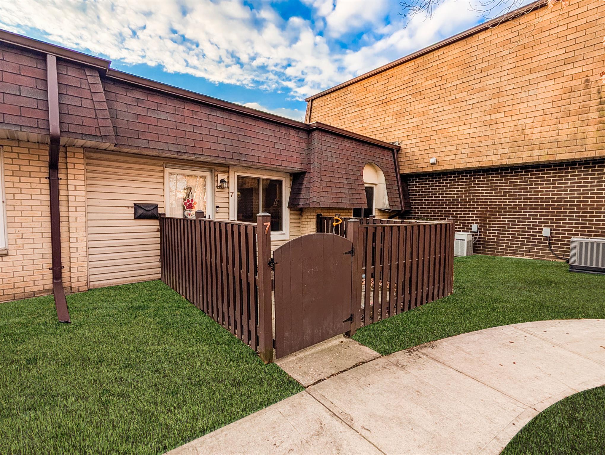 View of property exterior with a lawn and cooling unit