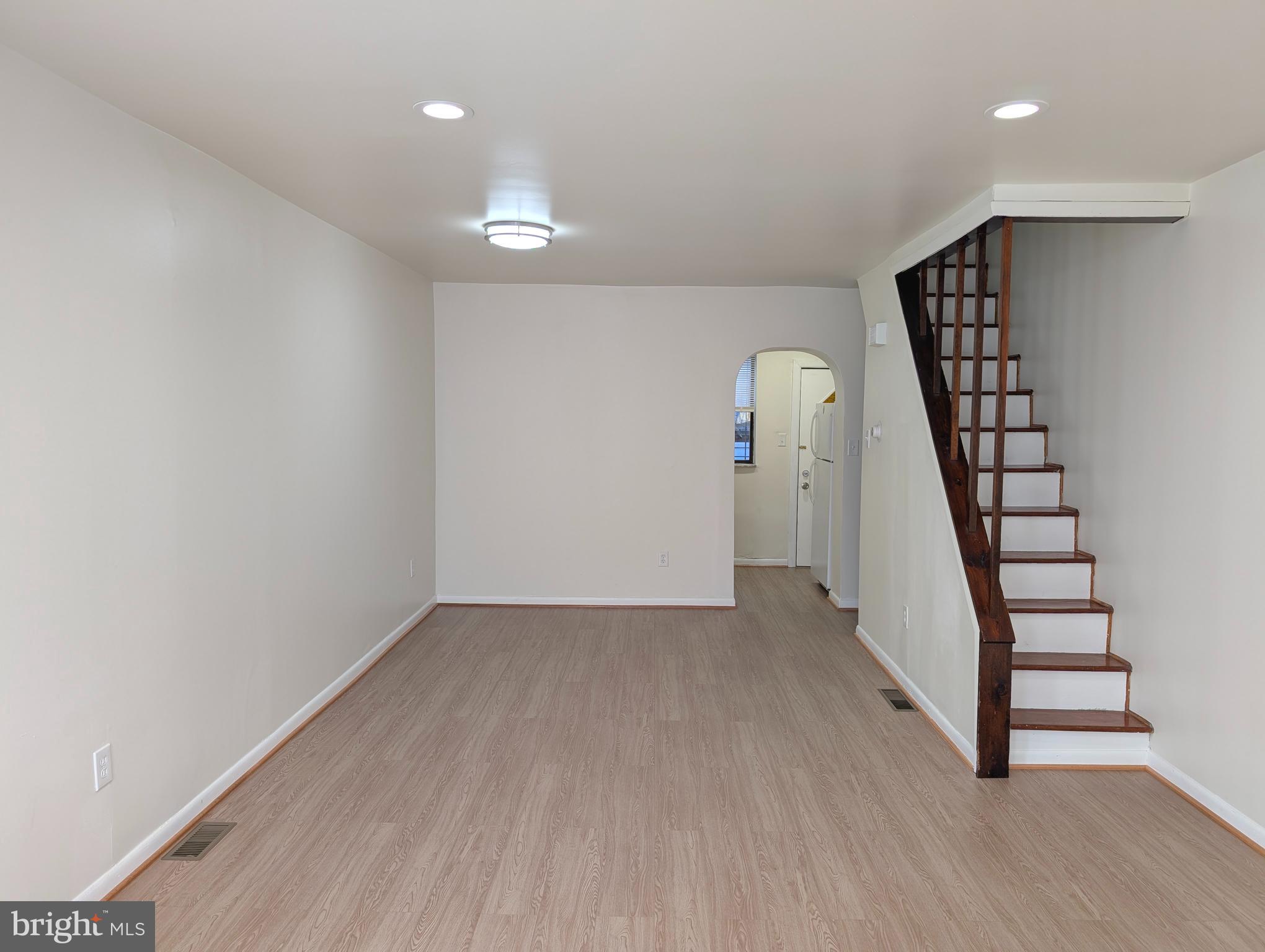 an empty room with wooden floor and staircase