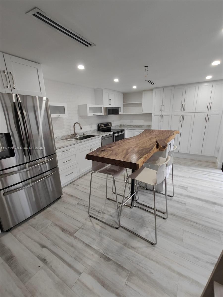 a kitchen with stainless steel appliances wooden floor and chairs in it