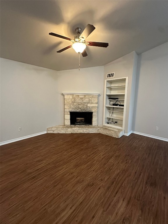 a view of an empty room with wooden floor fireplace and a window