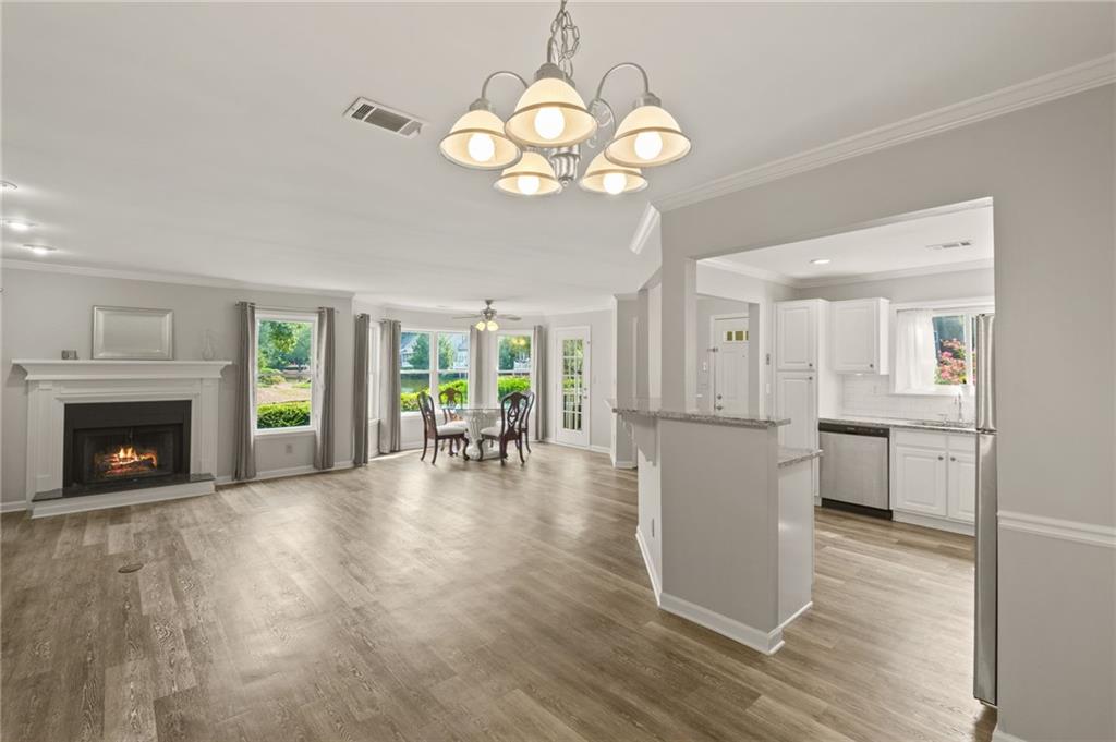 a view of a livingroom with furniture a fireplace wooden floor and chandelier