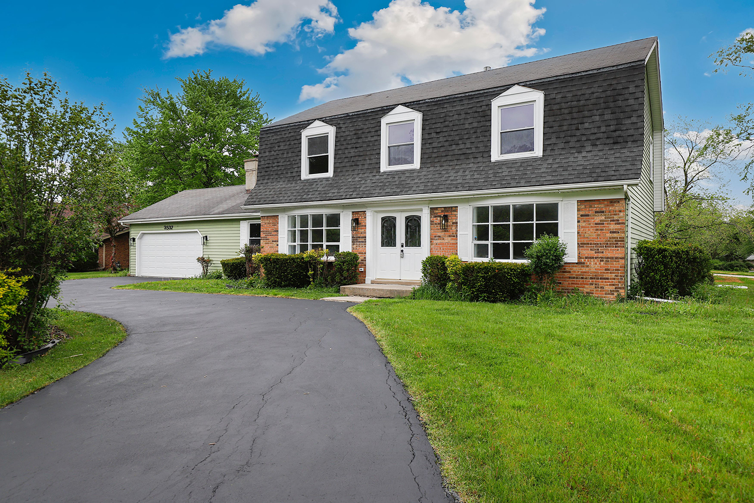 a front view of a house with a yard and potted plants