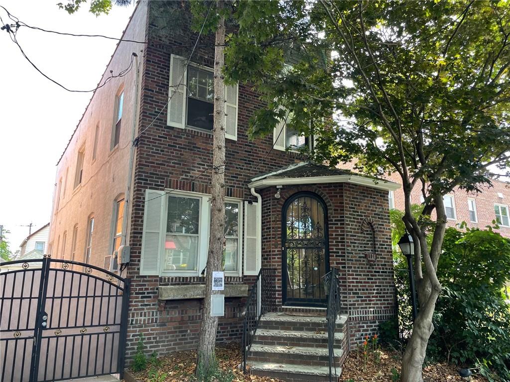 a view of a brick house with large windows and a small yard