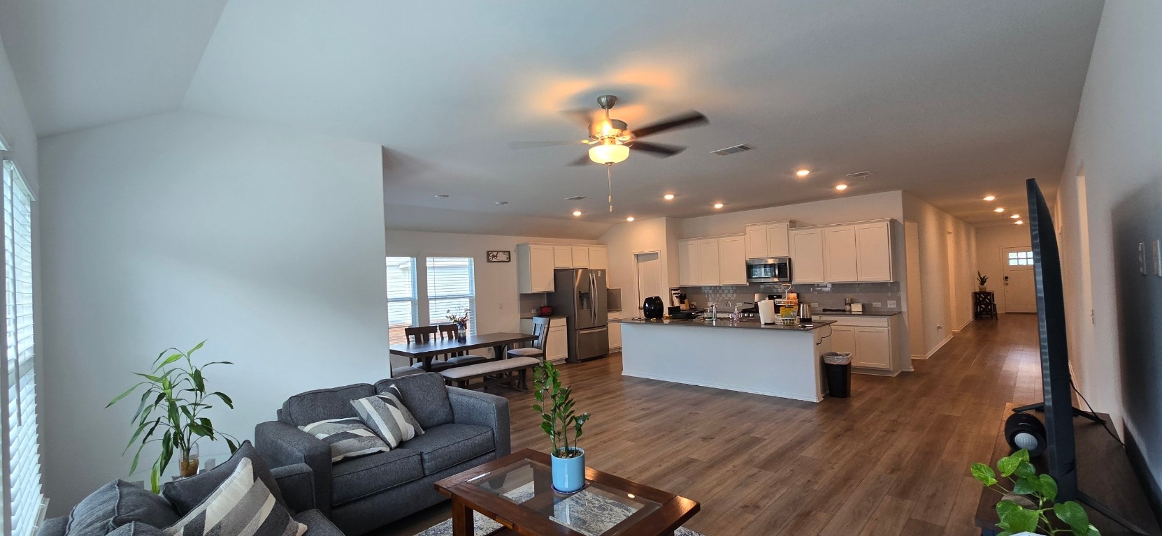 a living room with furniture kitchen view and a wooden floor