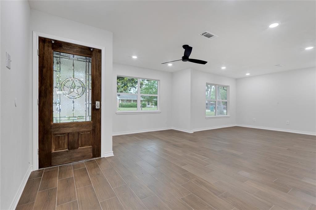 an empty room with wooden floor and windows