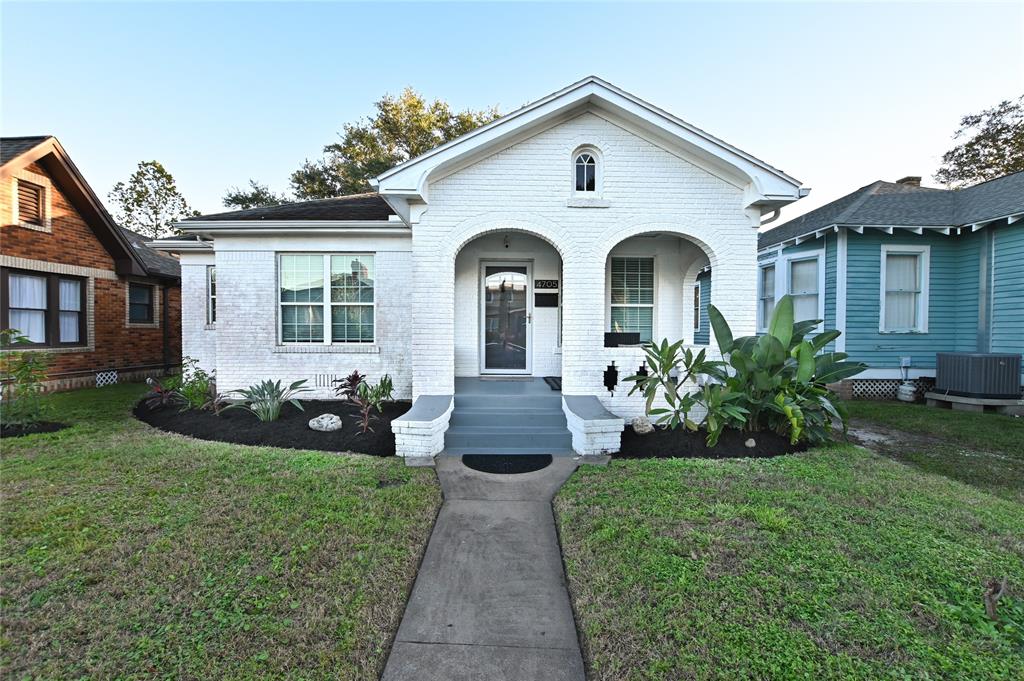 Charming Tudor Cottage with a classic arched entryway, accented by manicured landscaping.