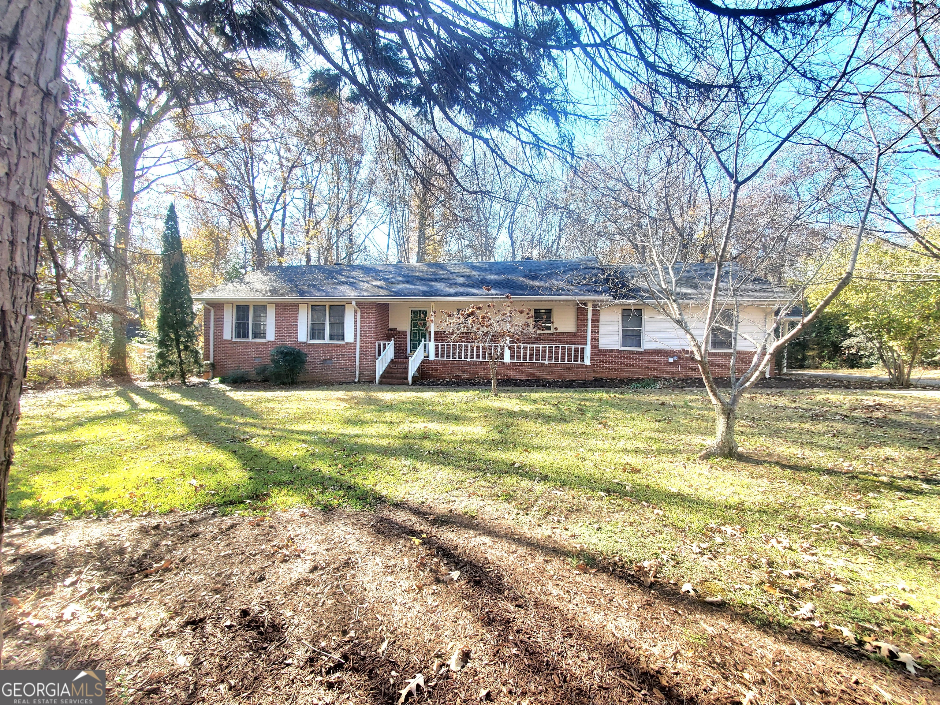 a view of a house with a yard and large trees