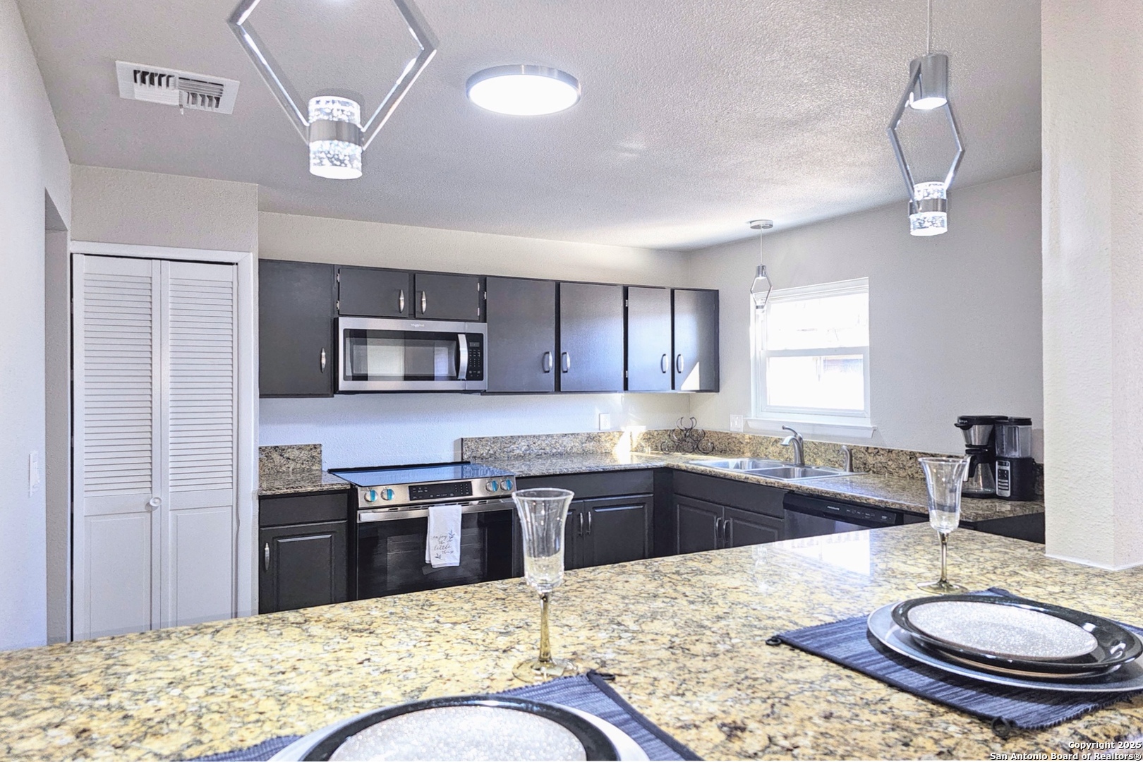 a kitchen with stainless steel appliances granite countertop a stove a sink a refrigerator dining table and chairs