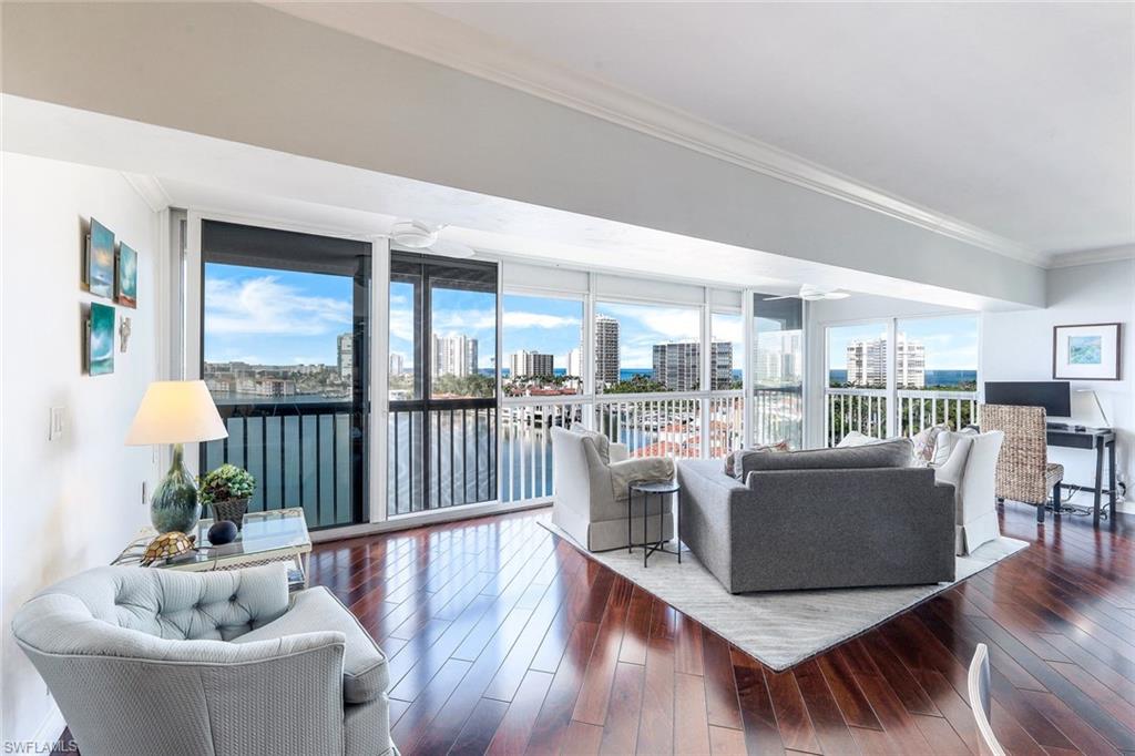 a living room with furniture a floor to ceiling window and wooden floor