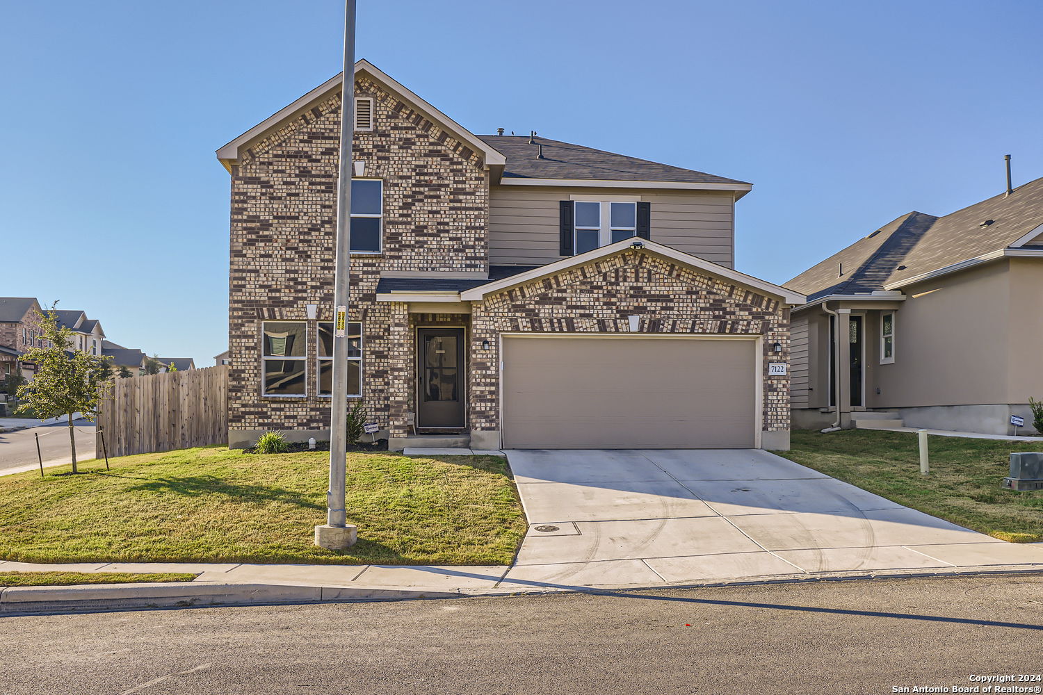 a view of a house with a small yard and large parking space