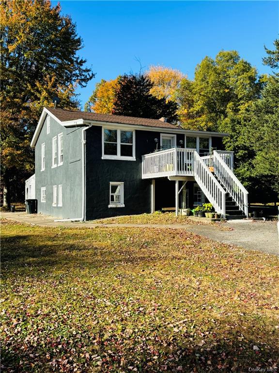 View of front of home with a wooden deck and a front lawn