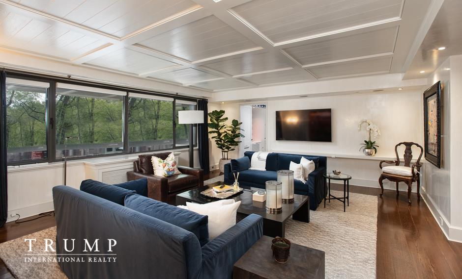 a living room with furniture floor to ceiling window hardwood floor and a flat screen tv