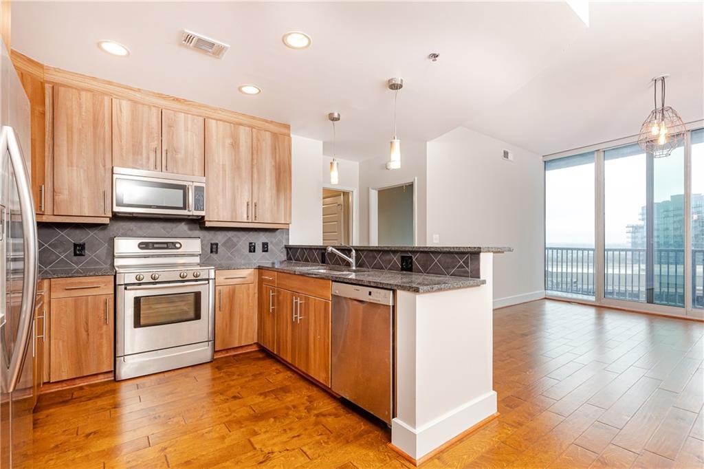 a kitchen with stainless steel appliances granite countertop a stove a sink and a microwave