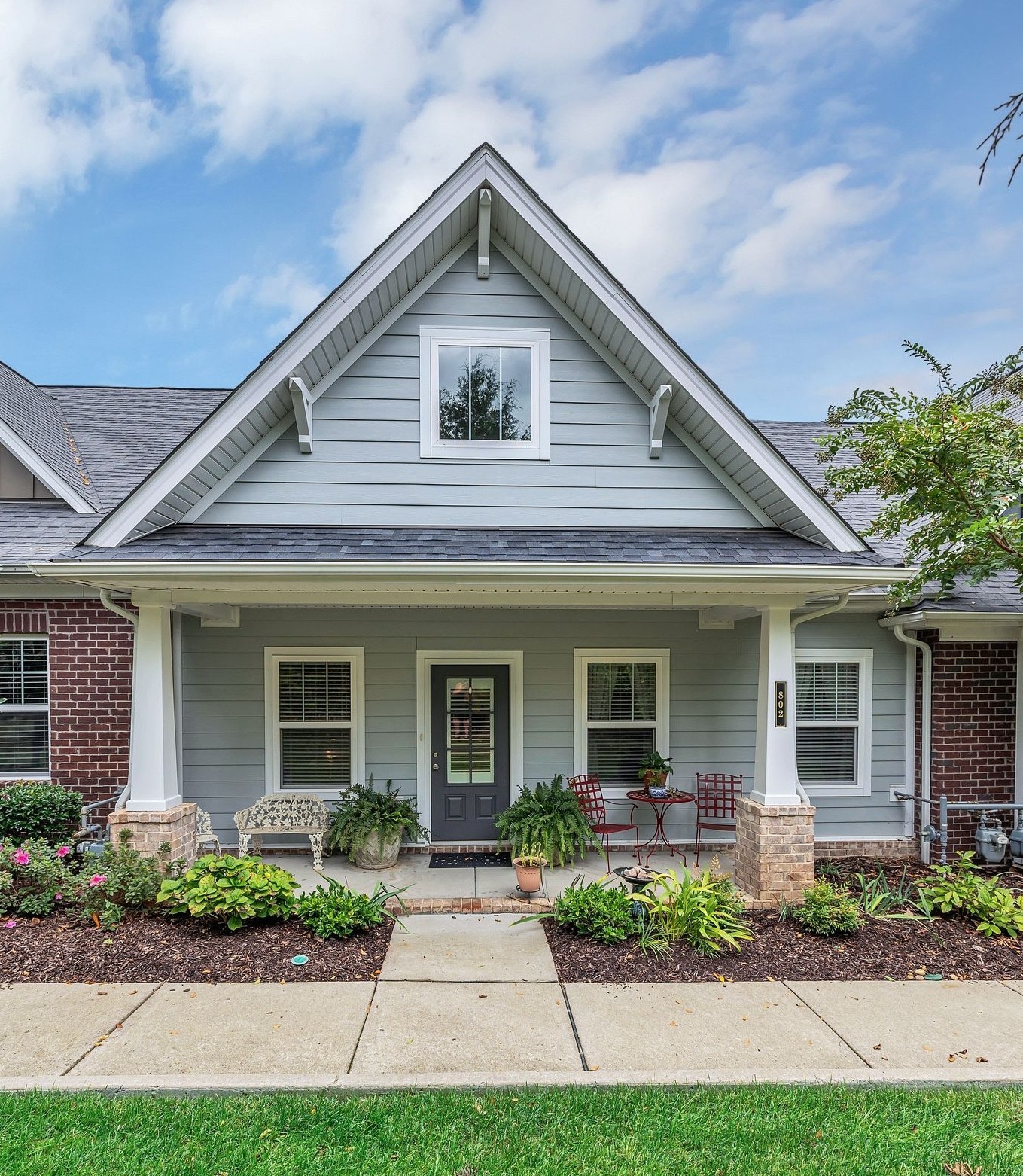 a front view of a house with a yard and potted plants