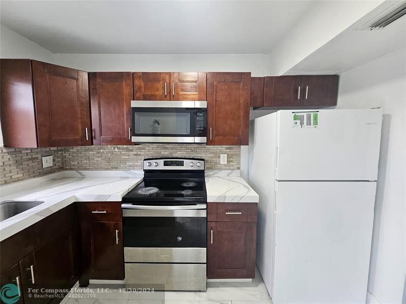 a kitchen with a refrigerator a stove a microwave and cabinets