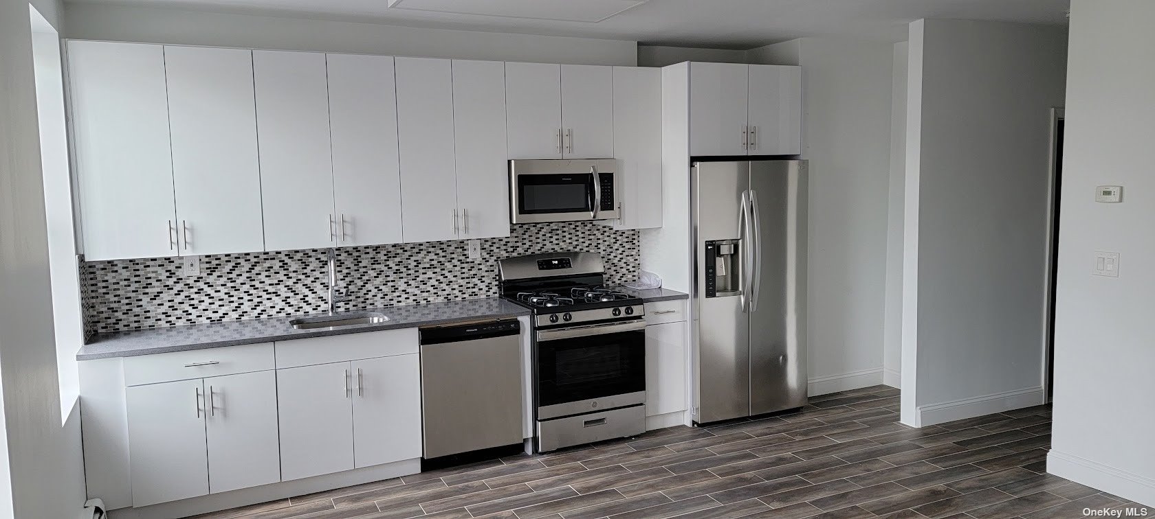 a kitchen with granite countertop white cabinets and stainless steel appliances