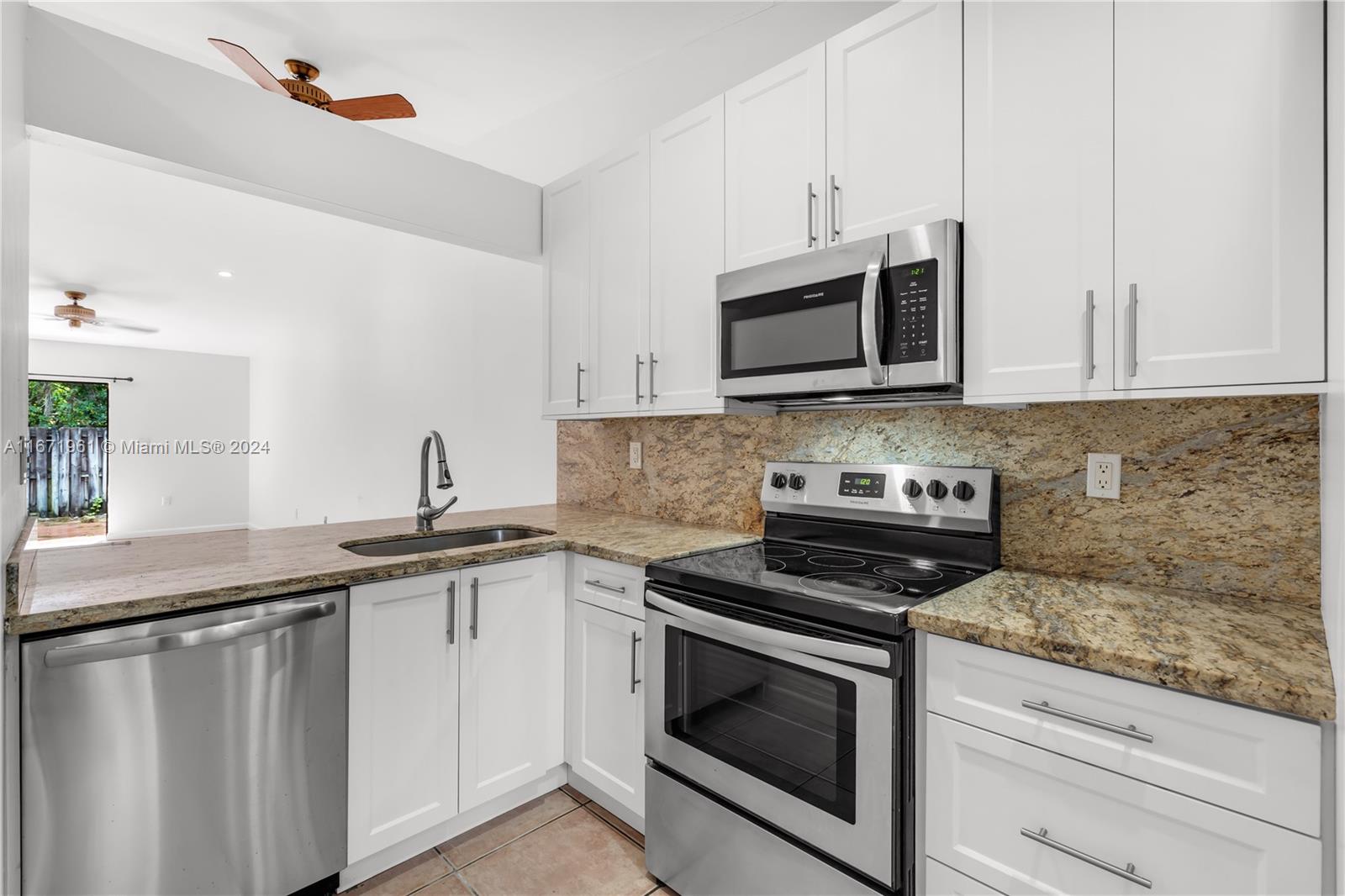 a kitchen with granite countertop a sink cabinets and stainless steel appliances