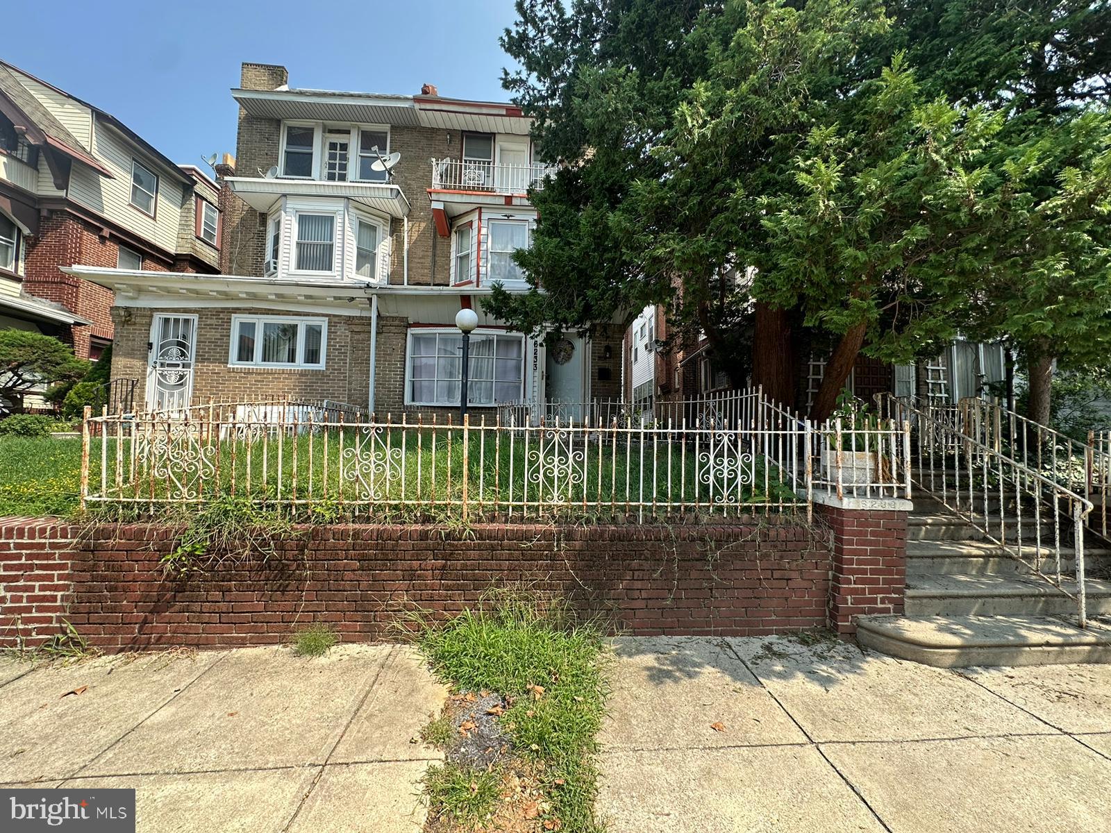 a view of a brick house with a small yard and wooden fence