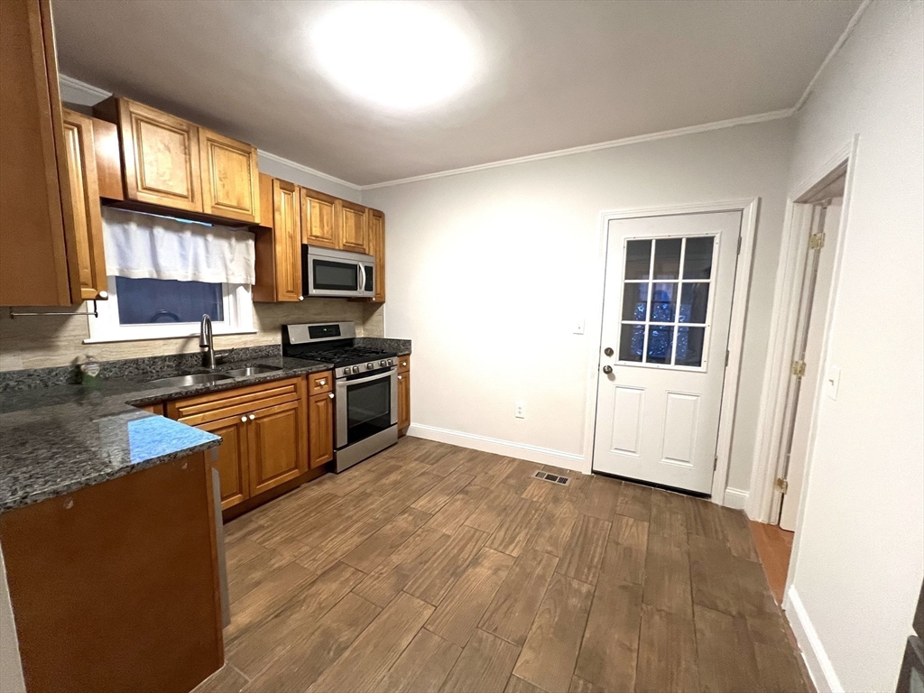 a kitchen with granite countertop a stove a sink and a microwave