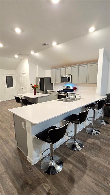 a kitchen with kitchen island stainless steel appliances a sink a counter top space appliances and cabinets