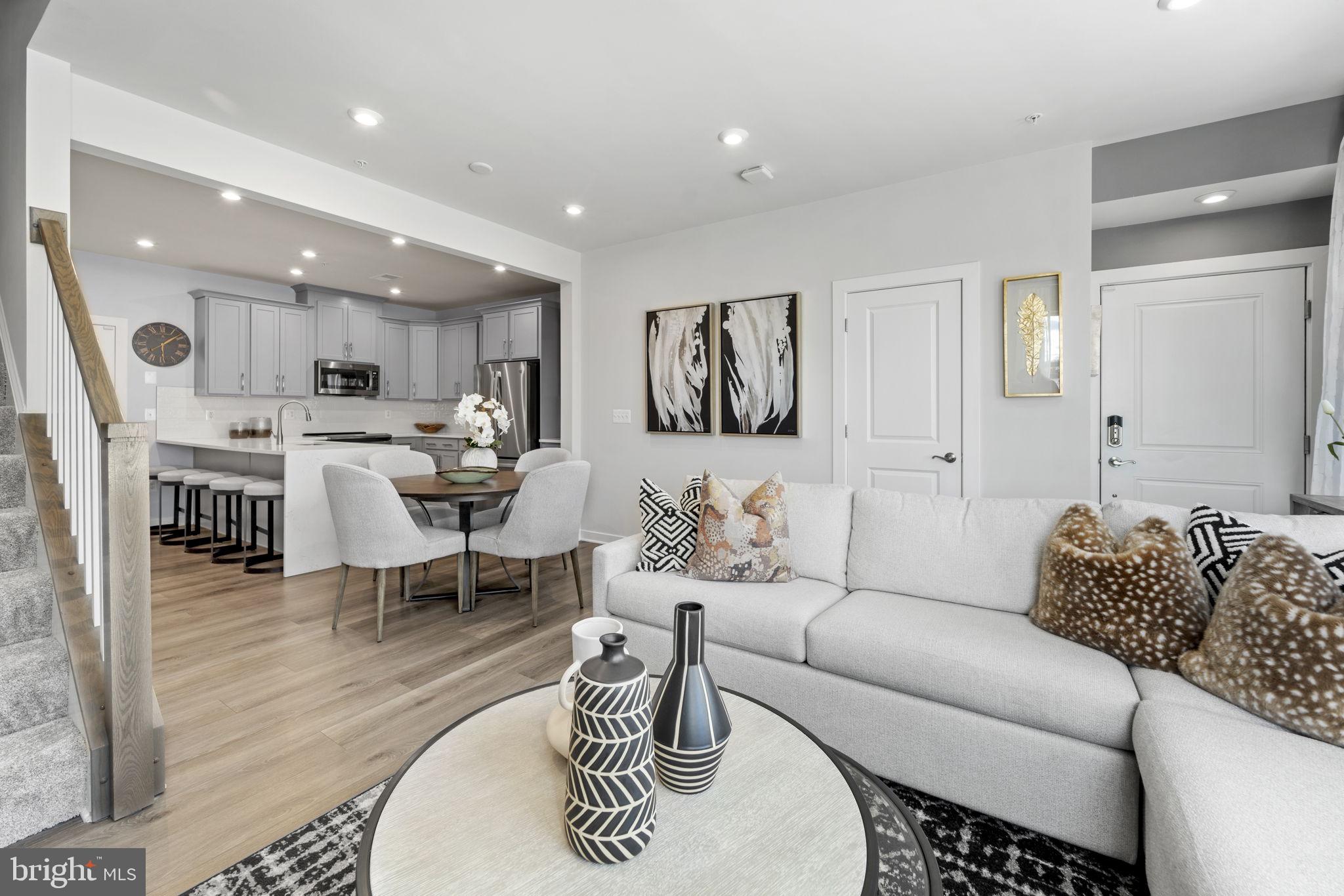 a living room with furniture kitchen view and a wooden floor