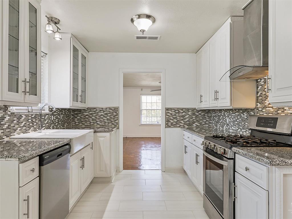 a kitchen with granite countertop a sink stove and cabinets