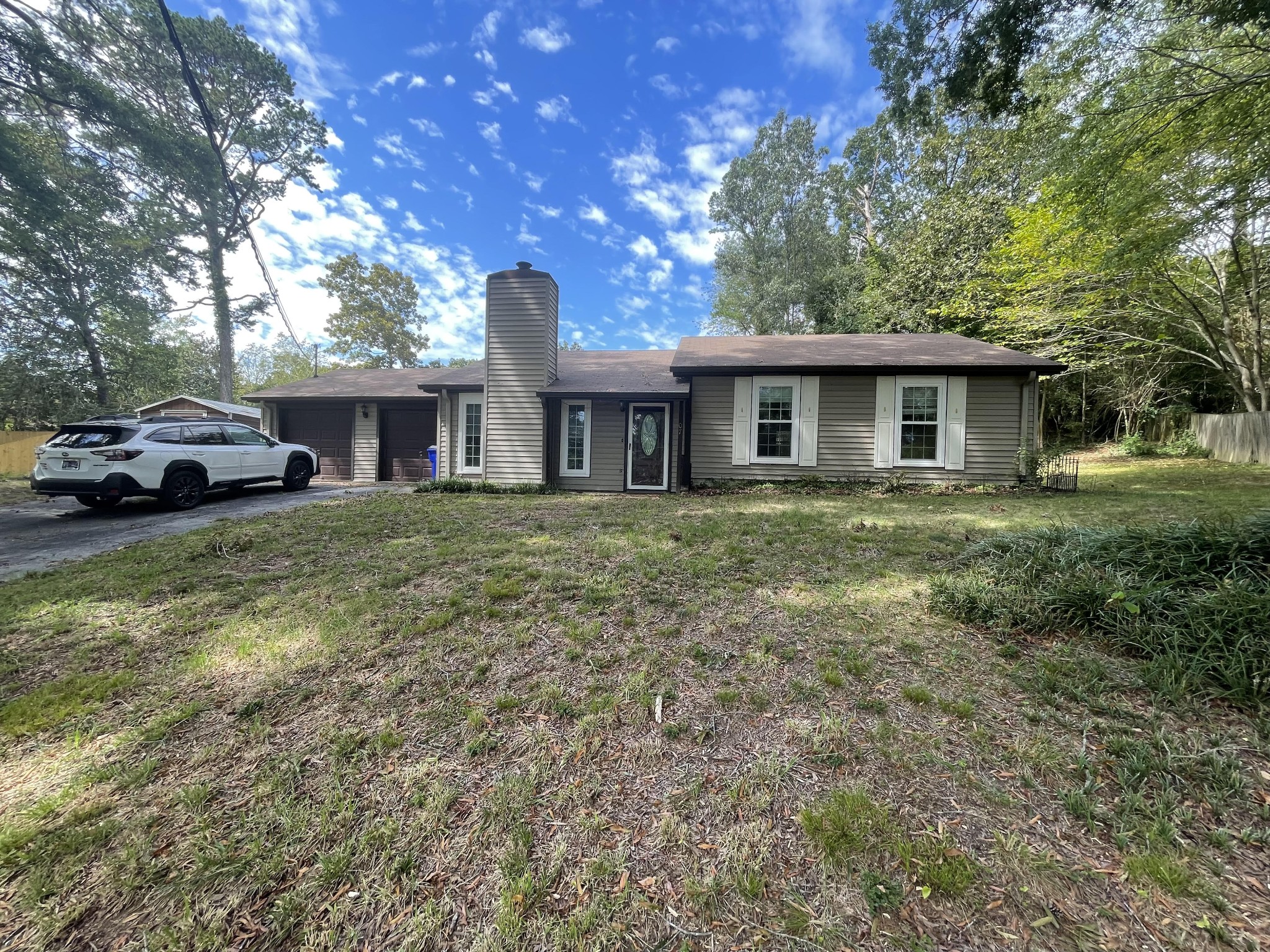 a view of house with a big yard and large trees