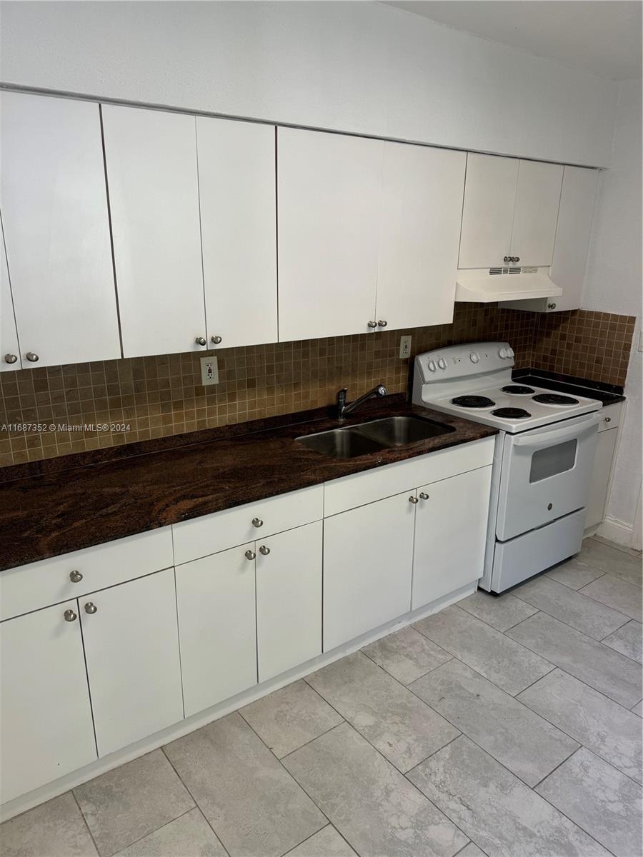 a kitchen with granite countertop white cabinets and white appliances