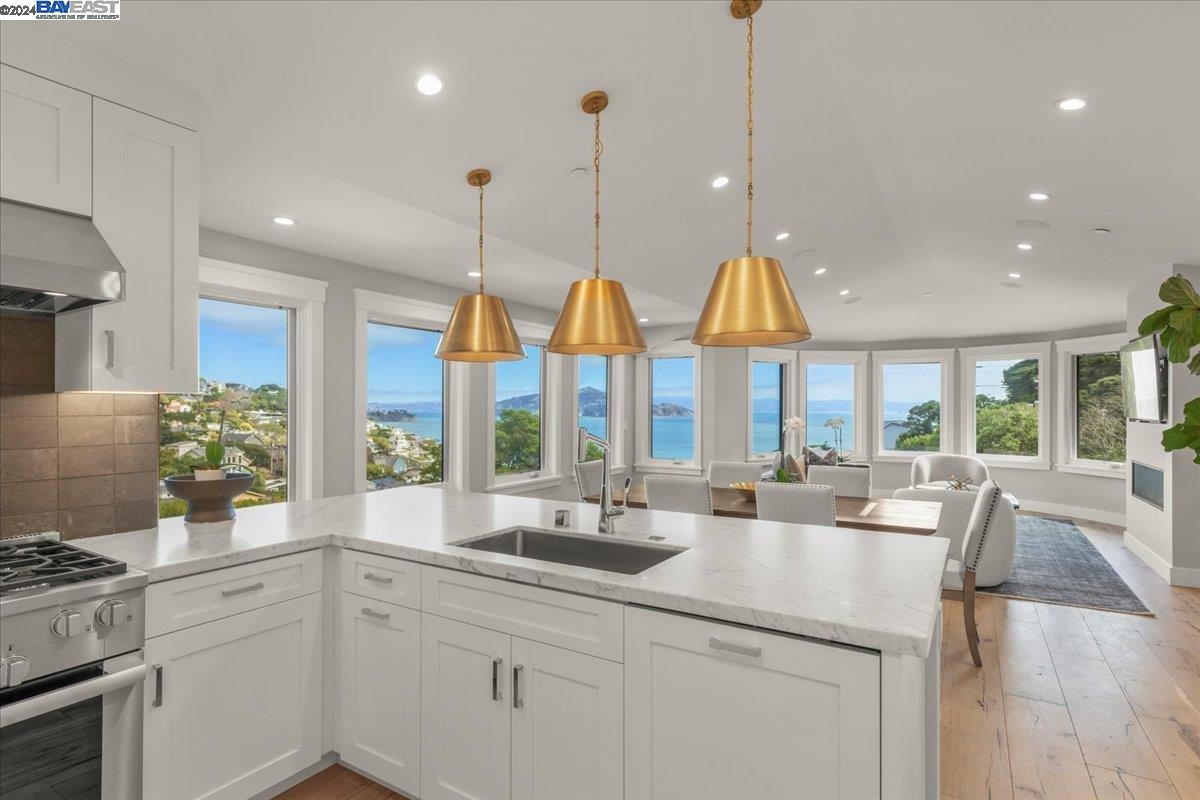 a kitchen with stainless steel appliances granite countertop a sink a stove and a wooden floors