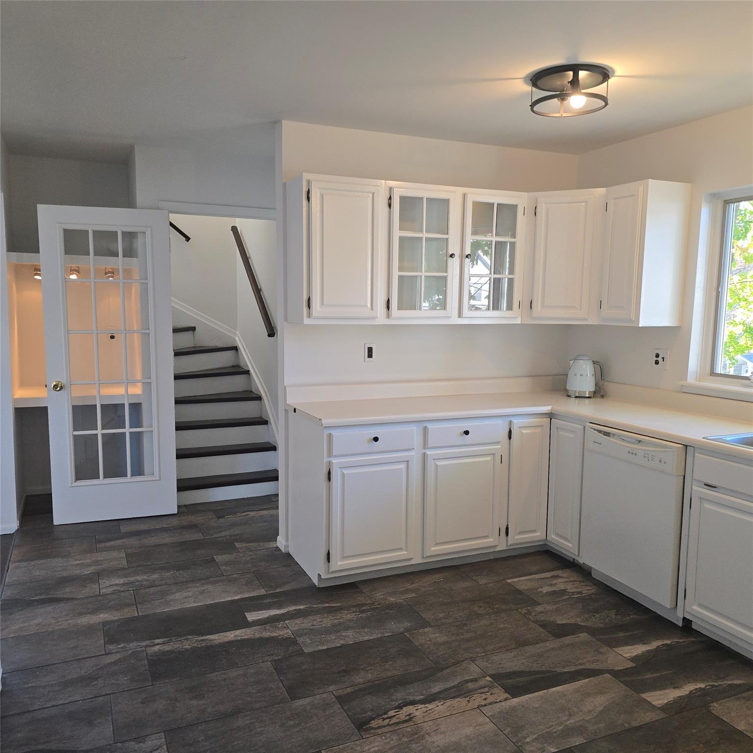 Kitchen featuring white cabinets, dark wood-type flooring, and dishwasher