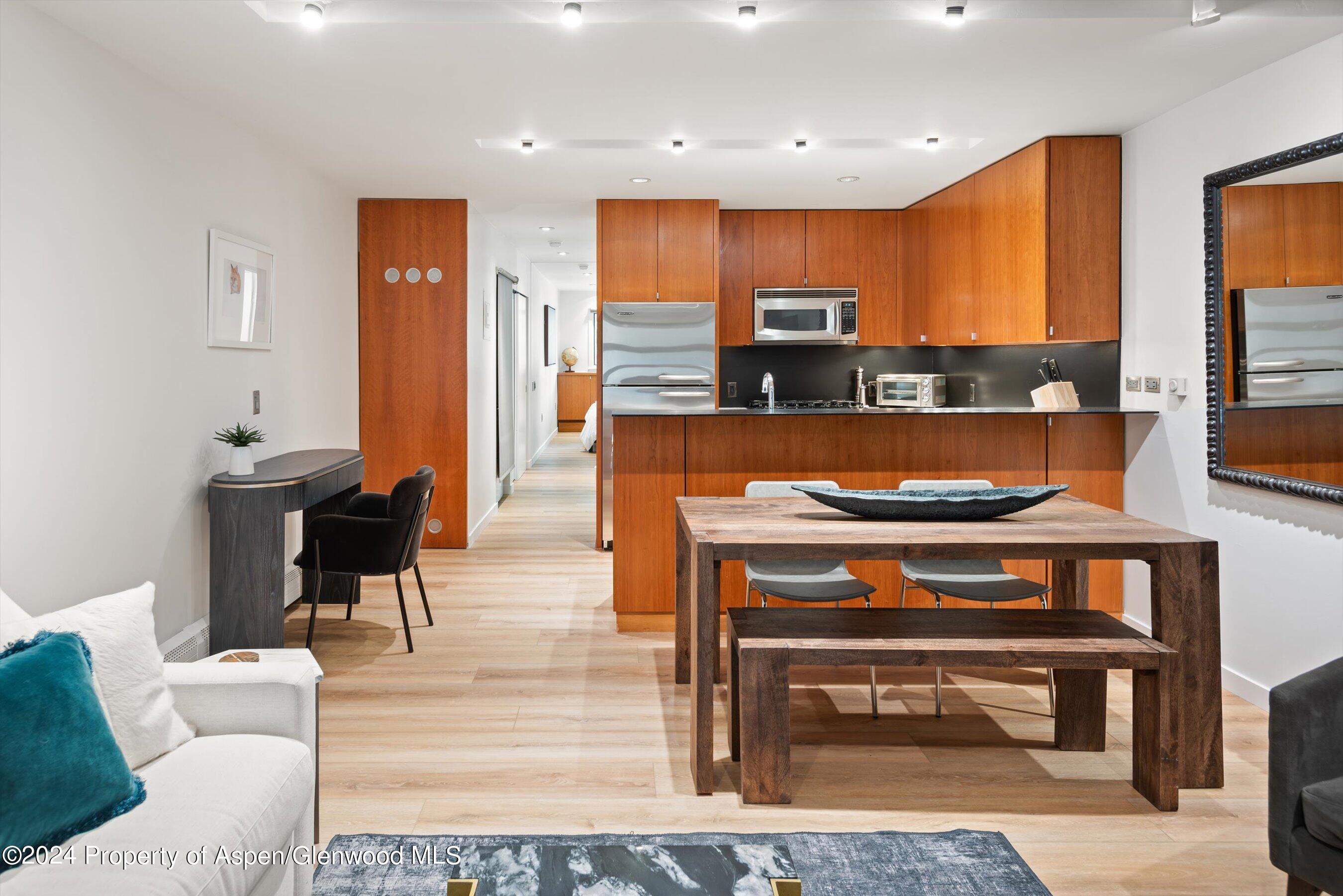 a living room with stainless steel appliances furniture a rug and a view of kitchen