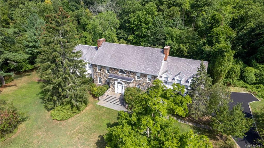 an aerial view of a house with yard and trees all around