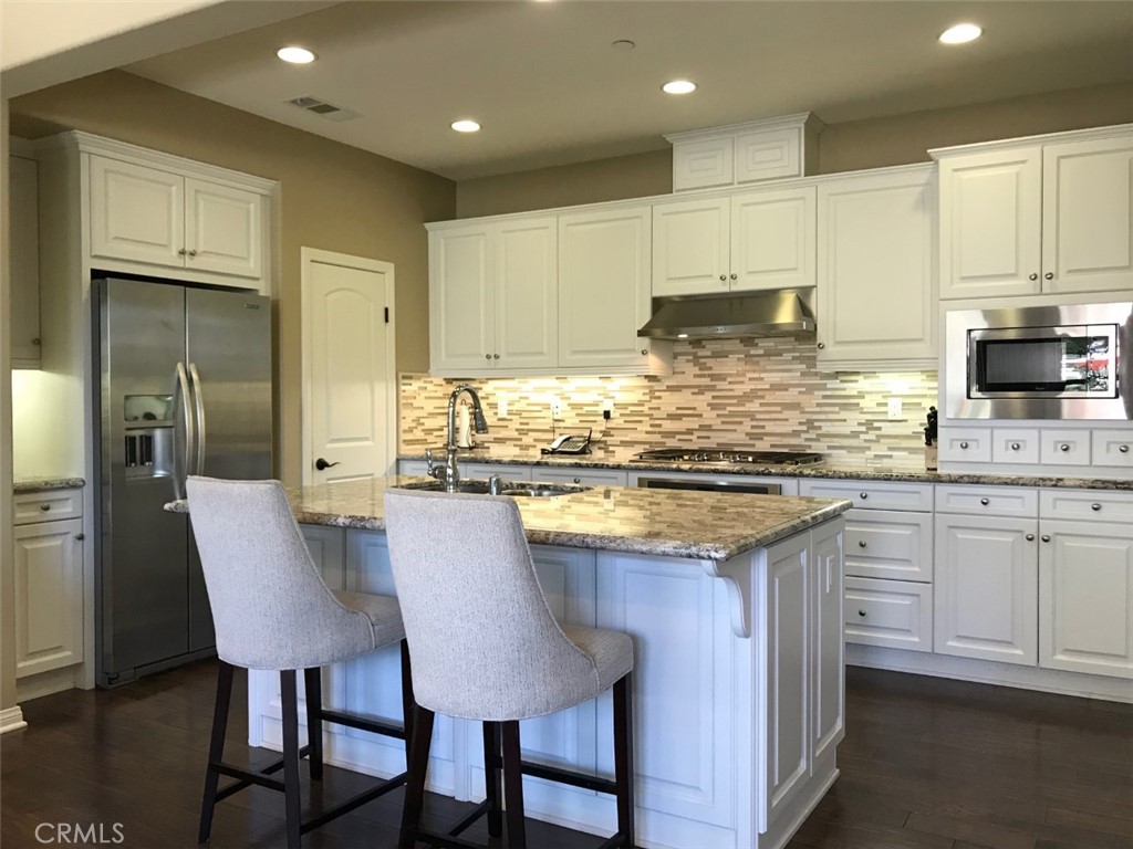 a kitchen with kitchen island granite countertop a table chairs sink and cabinets