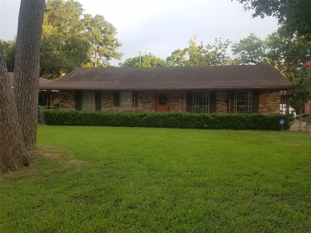 a view of house in front of a big yard with large trees