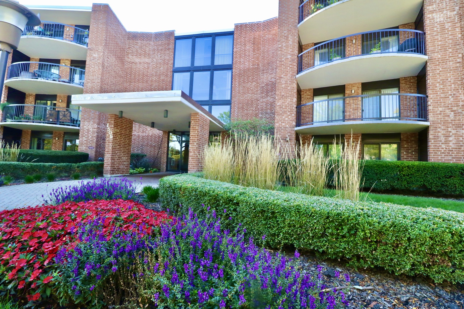 a front view of a multi story residential apartment building with yard and green space