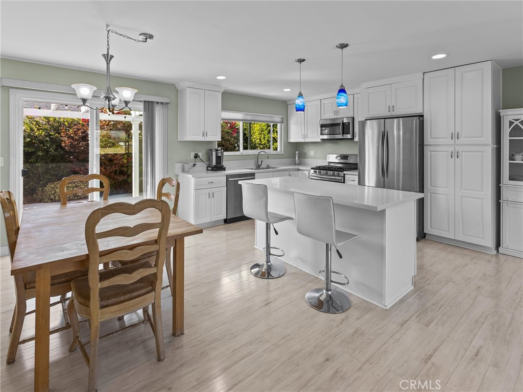 a kitchen with stainless steel appliances kitchen island granite countertop a table chairs and a refrigerator