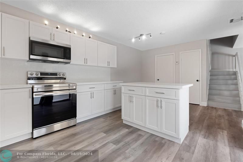 a kitchen with white cabinets stainless steel appliances and wooden floor