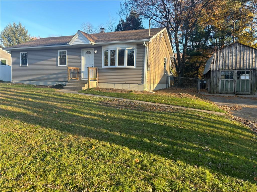 View of front of house with a front yard and a storage shed